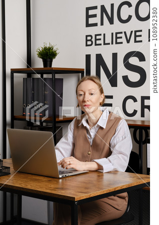 Middle aged woman is working at a laptop utilizing wireless technology Middle aged woman is working at a laptop utilizing wireless technology 108952380