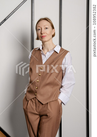 Young adult woman in suite holds her hands in pockets Young adult woman in suite holds her hands in pockets 108952382