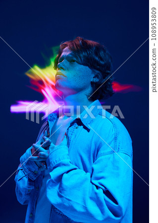 Confused man put hands on breast and looking away in mixed neon light illuminating futuristic, digital projector reflection. Confused man put hands on breast and looking away in mixed neon light illuminating futuristic, digital projector reflection. 108953809