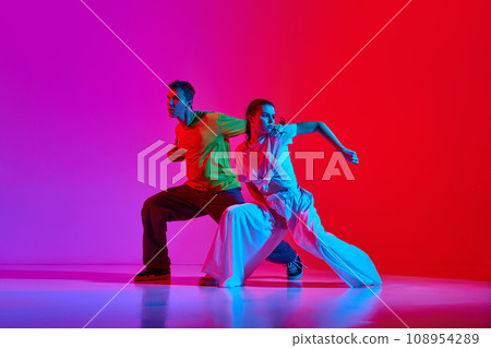 Young talented people, man and woman dancing street style dance, hip hop against pink red background in neon light Young talented people, man and woman dancing street style dance, hip hop against pink red background in neon light 108954289