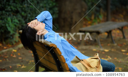 A worried woman sitting on a bench 108954763