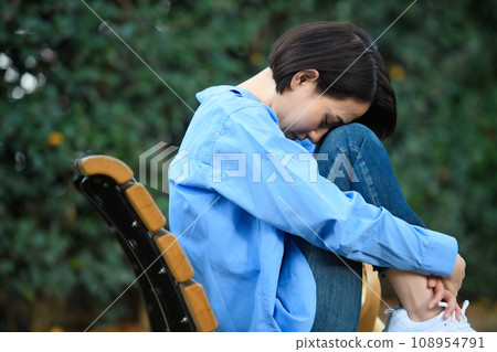 一個憂心忡忡的女人坐在長凳上 108954791