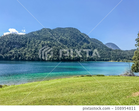 Huge mountain blue lake. Untouched wildlife of Europe. Majestic mountains covered with trees rise above the turquoise clean lake Huge mountain blue lake. Untouched wildlife of Europe. Majestic mountains covered with trees rise above the turquoise clean lake 108954811