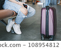 Travel, airport. A woman with a suitcase is waiting for a plane sitting at the airport. 108954812