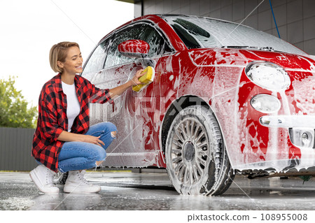Blonde woman cleaning the car door with a foam 108955008