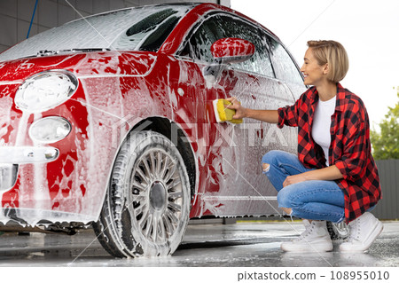 Blonde woman cleaning the car door with a foam 108955010