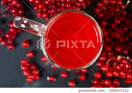 Hot viburnum tea in a glass cup with a double bottom on a black background. 108955532