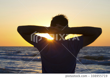 Young man hands behind head relax at sunrise sky sea 108955719