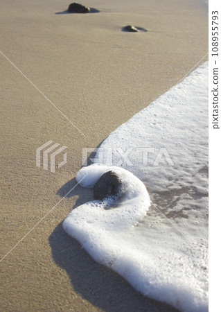 Stone in foam from sea wave on sand sunrise sea 108955793