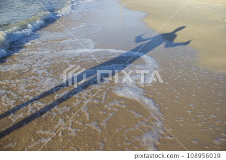 Shadow young man with his hands up at sunrise, sea 108956019
