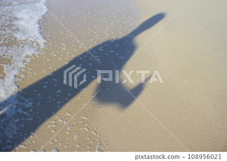Shadow young man with his hands up at sunrise, sea 108956021