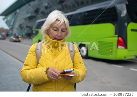 Tourist is waiting a taxi. Senior woman stand outside airport and wait for taxi cab after vacation or travel.  108957225