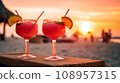 Two watermelon sex on the beach glasses of cocktail with lime slice on blur beach with sunset, sky and palm on background.  108957315