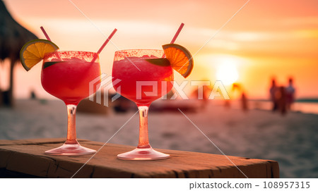Two watermelon sex on the beach glasses of cocktail with lime slice on blur beach with sunset, sky and palm on background. Two watermelon sex on the beach glasses of cocktail with lime slice on blur beach with sunset, sky and palm on background. 108957315