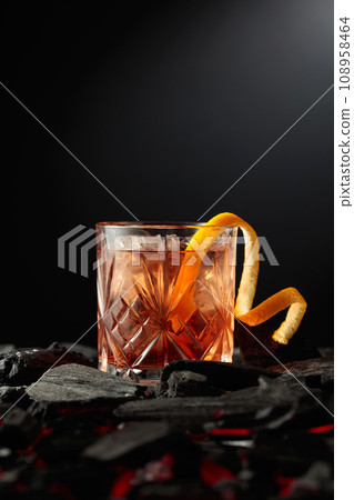 Old-fashioned cocktail with ice and orange peel. 108958464