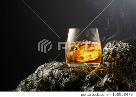 Whiskey with ice and smoke on a grey stone. 108958476