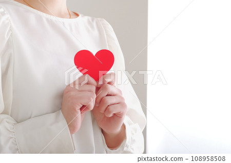 一個女人胸前抱著一個心形物體 108958508