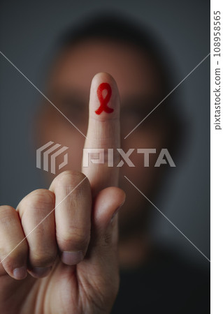 man with a red ribbon painted in his forefinger 108958565