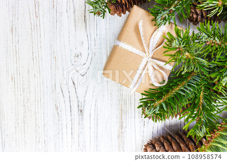 Wrapped Christmas gifts on dark rustic wooden table with pine cones and fir branches. With copy space for your text 108958574