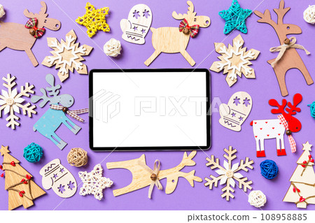 Festive decorations and toys on purple background. Top view of digital tablet. Merry Christmas concept 108958885