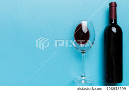 Glass of red wine and a bottle on colored table. Flat lay, top view wth copy space Glass of red wine and a bottle on colored table. Flat lay, top view wth copy space 108958899