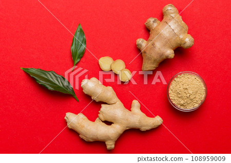 Finely dry Ginger powder in bowl with green leaves isolated on colored background. top view flat lay Finely dry Ginger powder in bowl with green leaves isolated on colored background. top view flat lay 108959009