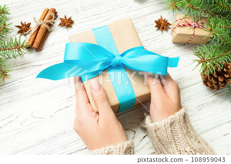 Female hands holding handmade present box in recycled paper on white wooden table background. christmas preparation concept, Gift wrapping background 108959043