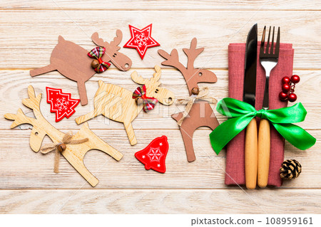 New year set of fork and knife on napkin. Top view of christmas decorations and reindeer on wooden background. Close up of holiday family dinner concept 108959161