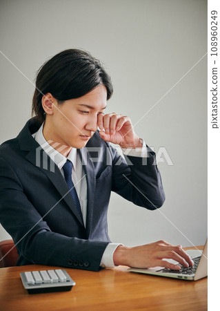 A young male office worker has itchy eyes and rubs them with his fingers A young male office worker has itchy eyes and rubs them with his fingers 108960249