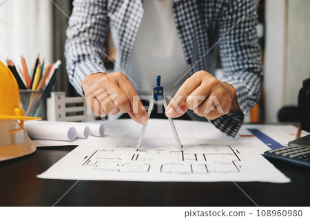 Creative architect projecting on the big drawings with architectural project at construction site at desk in office Creative architect projecting on the big drawings with architectural project at construction site at desk in office 108960980