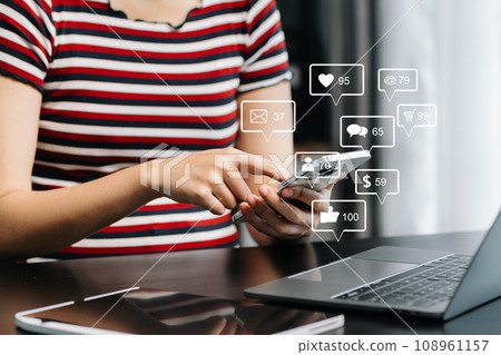 Asian woman typing smartphone, keyboard with laptop computer of Social media and Marketing virtual icons screen concept.. Asian woman typing smartphone, keyboard with laptop computer of Social media and Marketing virtual icons screen concept.. 108961157