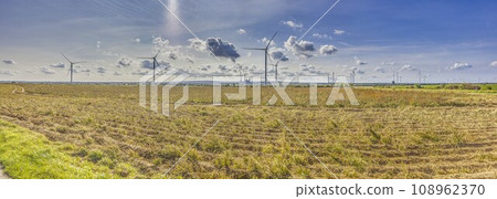 Panoramic image of a wind farm with a coal-fired power plant in the background 108962370