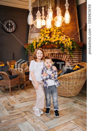 Little brother and sister hugging in the interior of a country house. 108963656