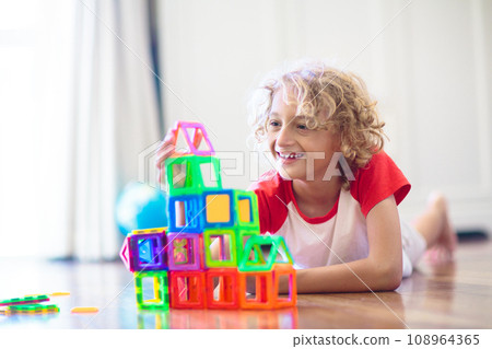 Child playing with magnetic building blocks. 108964365