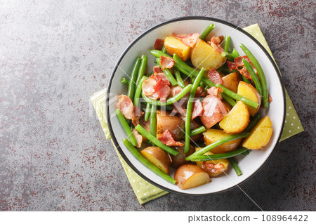 Crunchy bacon, green beans, potatoes in a vinegar dressing closeup on the plate. Horizontal top view Crunchy bacon, green beans, potatoes in a vinegar dressing closeup on the plate. Horizontal top view 108964422