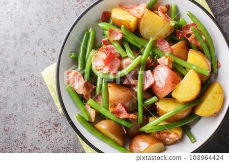 Warm jacket potato salad with bacon and green beans close-up in a bowl. Horizontal top view 108964424