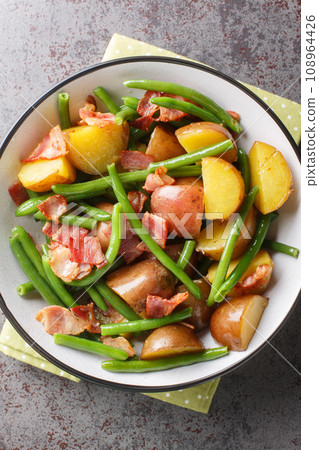 Salade Liegeoise Belgian Potato Salad is a warm potato salad with green beans, bacon and a mustard vinaigrette closeup on the plate. Vertical top view 108964426