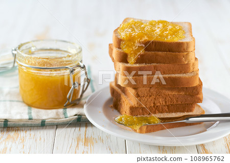 A stack of toasts with lemon jam on a dish close-up. Plate with pieces of toasted bread and tasty lemon jam. 108965762