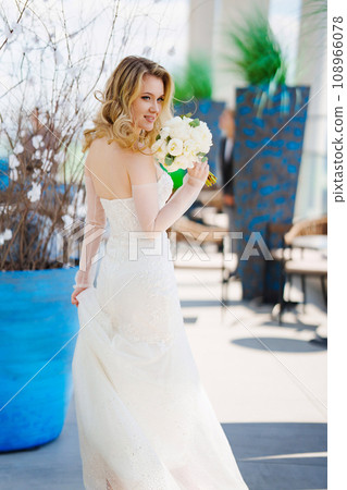 Beautiful blonde bride in a tight-fitting dress with a bouquet. Beautiful blonde bride in a tight-fitting dress with a bouquet. 108966078
