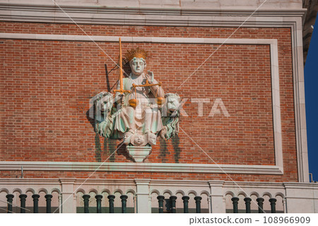 A regal woman in a flowing gown and crown stands atop a building, exuding strength and grace. The statue exudes authority and power, with a sense of royalty and importance. 108966909