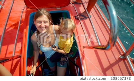 Happy smiling woman with baby son walking up the stairs on tourist submarine. Family holiday, summer vacation and tourism 108967378