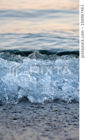 Macro shot of calm blue sea waves rolling and breaking on a sea beach on sunset 108967461