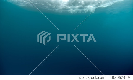 Underwater background of sun shining through water surface and sea waves going past 108967469