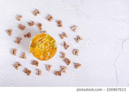 Chewable multivitamins in the form of candy bears in a bowl and wooden letters top view Chewable multivitamins in the form of candy bears in a bowl and wooden letters top view 108967613