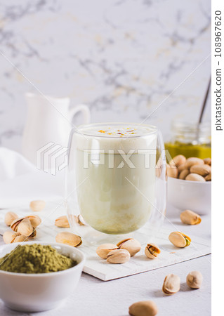 Matcha tea with pistachio spread in a glass and nuts on the table vertical view 108967620
