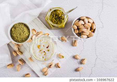 Matcha tea with pistachio spread in a glass and nuts on the table top view 108967622