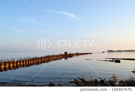 old wooden pier on the Baltic spit, Baltiysk, Kaliningrad region, fishermen at sunset 108967676