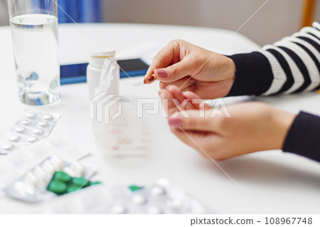 Woman hand putting pills into open pill organizer or plastic pillbox 108967748