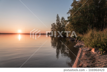 Lake with pine and birch forest on the shores at summer or early autumn sunset. Lake with pine and birch forest on the shores at summer or early autumn sunset. 108968420