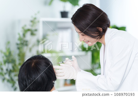 Cosmetic surgeon giving cosmetic injections 108970193